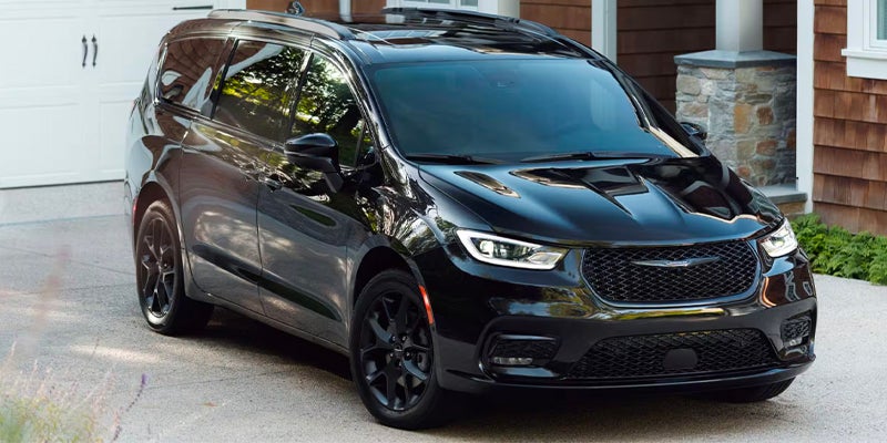 Black Chrysler Pacifica minivan parked on driveway of suburban home