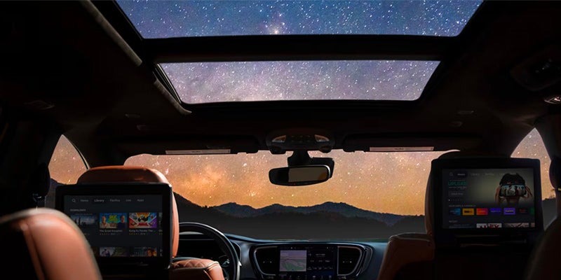 Interior view of car with starlit sky through sunroof and screens