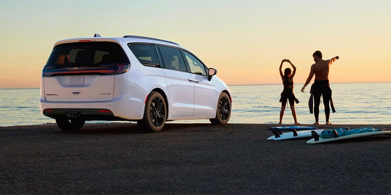 White Chrysler Pacifica Limited at beach with two people, sunset