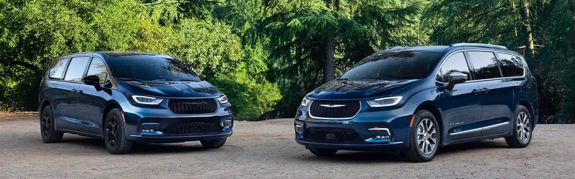 Two dark blue Chrysler Pacifica minivans parked in a wooded area
