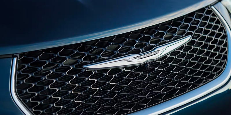 Close-up of Chrysler wing logo on dark blue vehicle grille