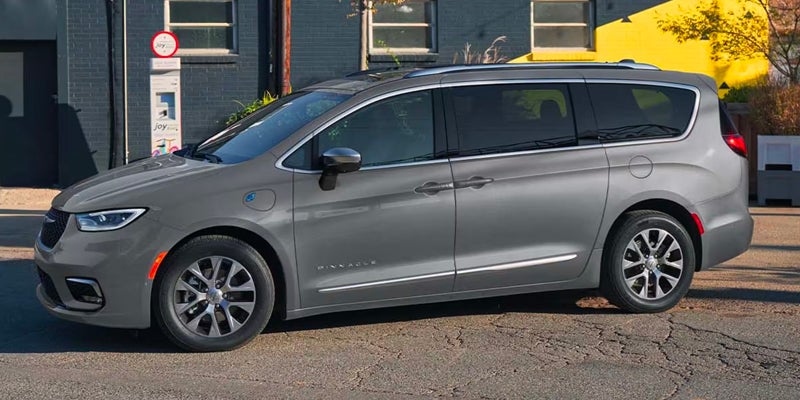 Side view of a gray Chrysler Pacifica Hybrid minivan parked outside