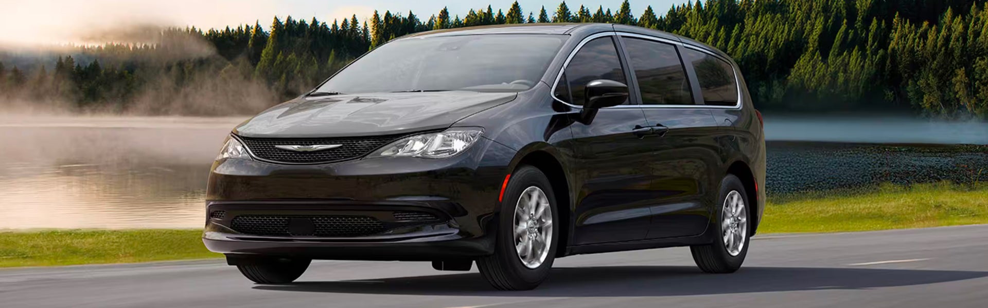 Black Chrysler Pacifica minivan driving on a scenic road