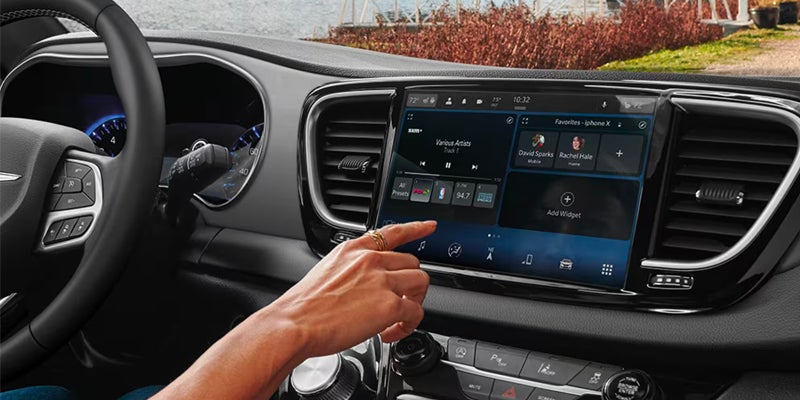 Hand touching a large infotainment screen in a minivan