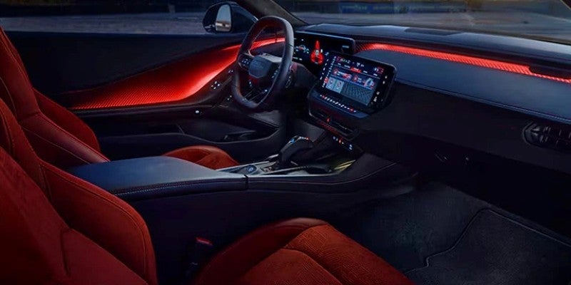 The interior of a car features red seats and ambient lighting