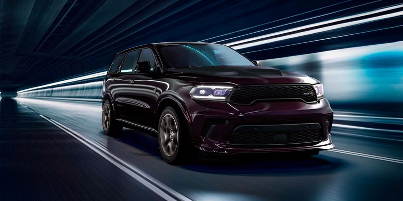 A dark purple Dodge Durango SRT driving through a futuristic tunnel