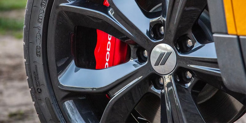 Close-up of a black wheel with a red "DODGE" branded brake caliper