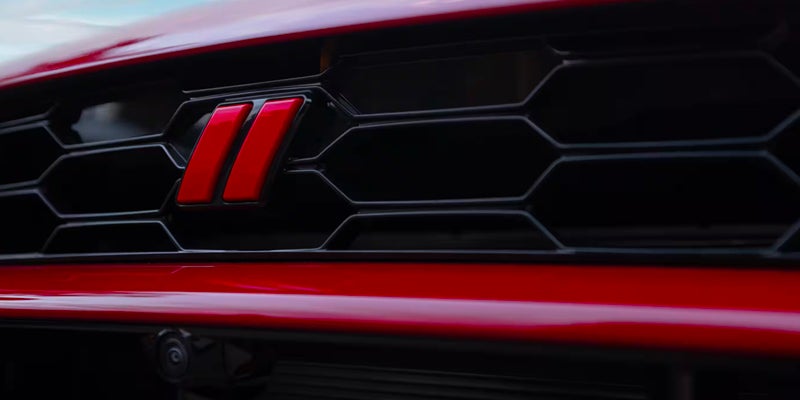 A close-up of a red "double hash mark" logo on a black grille