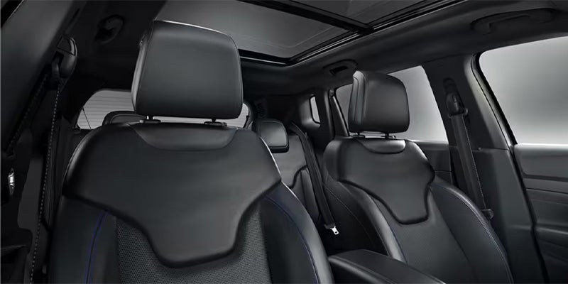 View of a car's dark interior with black leather seats and a panoramic sunroof.