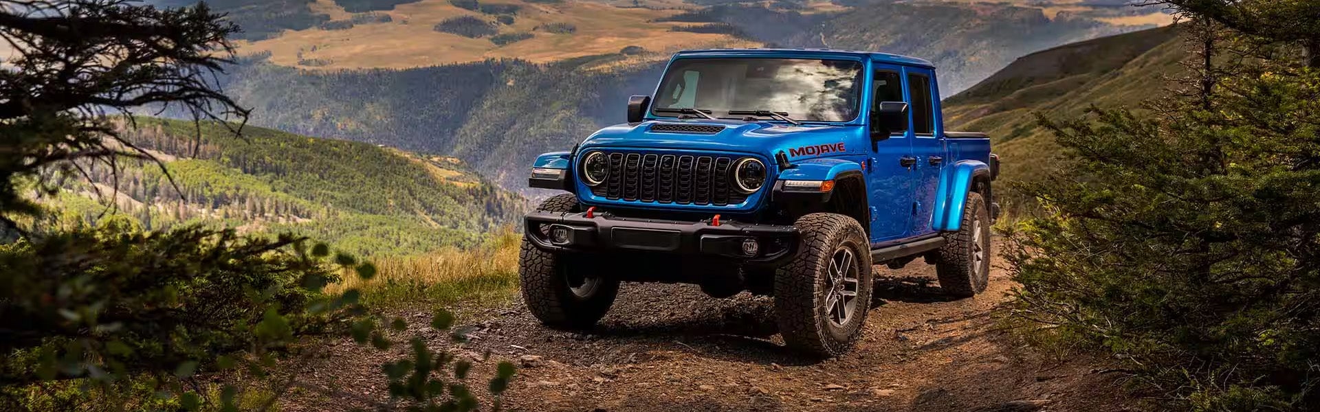 Blue Jeep Gladiator Mojave on a dusty mountain trail