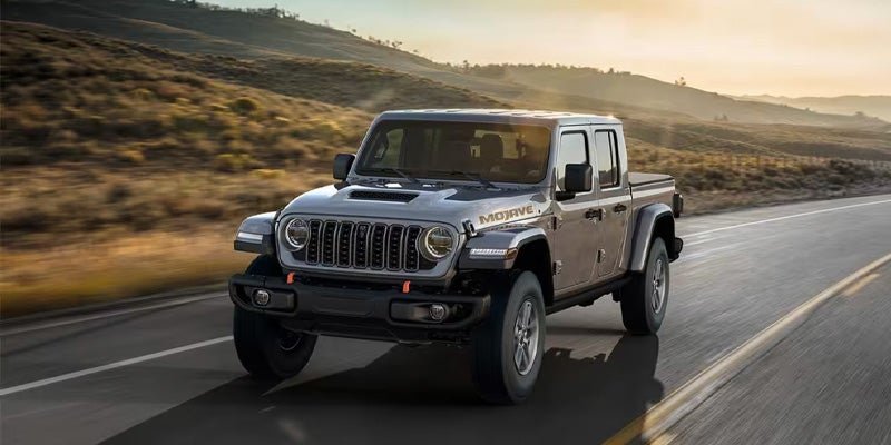 Gray Jeep Gladiator truck driving on a sunny desert road