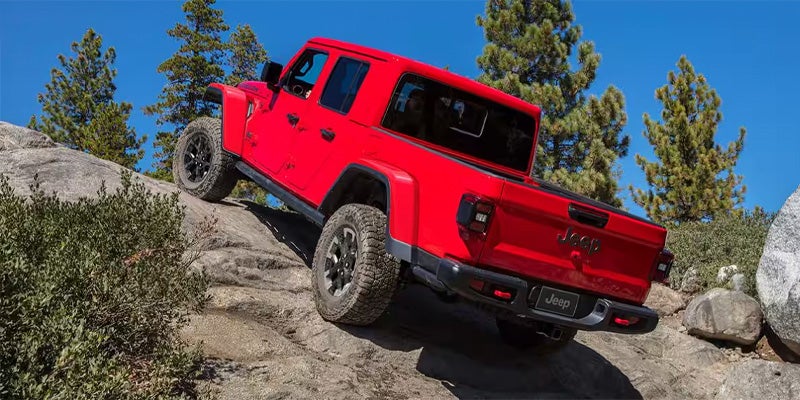 Red Jeep Gladiator truck climbing a rocky, steep hill