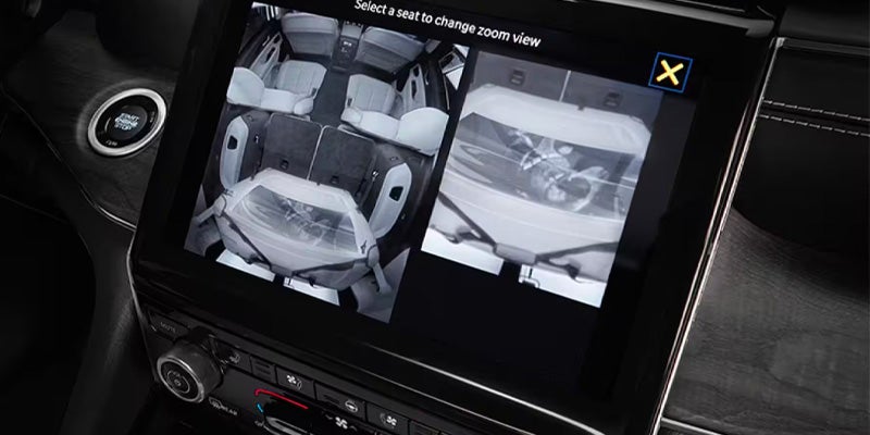 An infotainment display, showing two camera views of a car's interior with a white infant car seat.