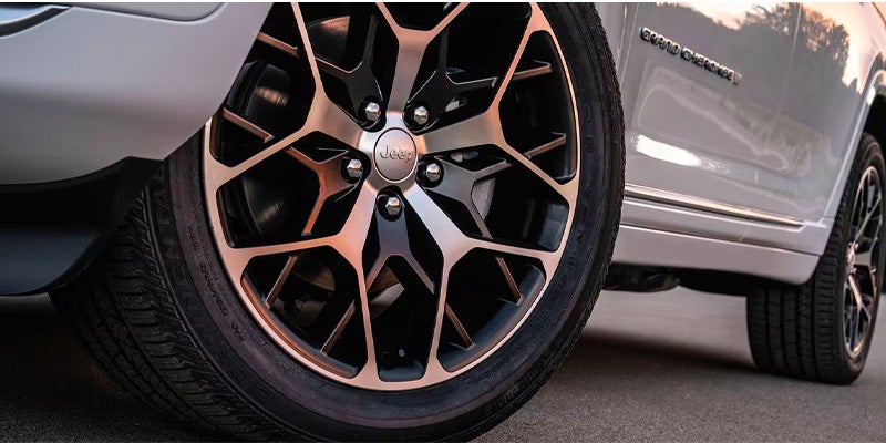 Close-up of a silver Jeep's front wheel with a black and bronze multi-spoke rim.