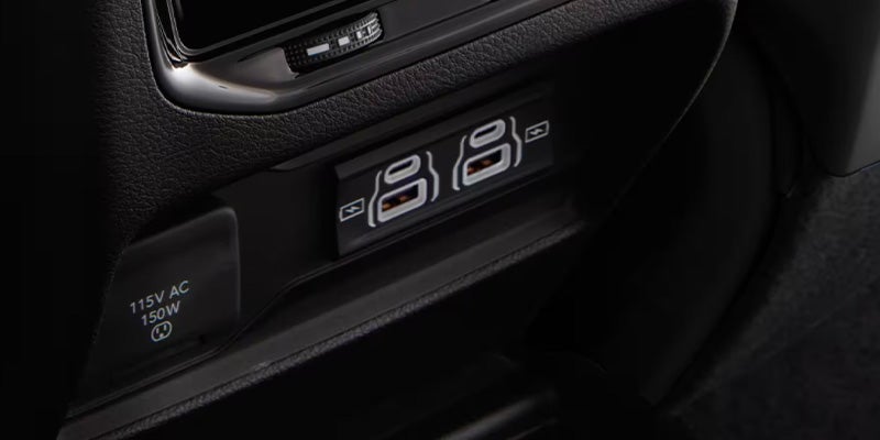 Close-up of a car's interior, showing a 115V AC 150W outlet and two USB-C ports