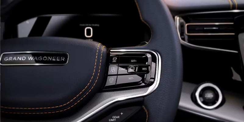 Close-up of a Grand Wagoneer steering wheel with "GRAND WAGONEER" embossed on the left center, and buttons on the right.