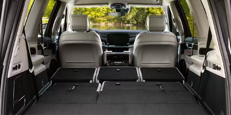 Back of an SUV with the third and second-row seats folded flat and gray front seats visible.