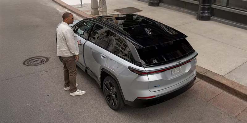 Man standing by the rear of a silver Jeep Wagoneer S