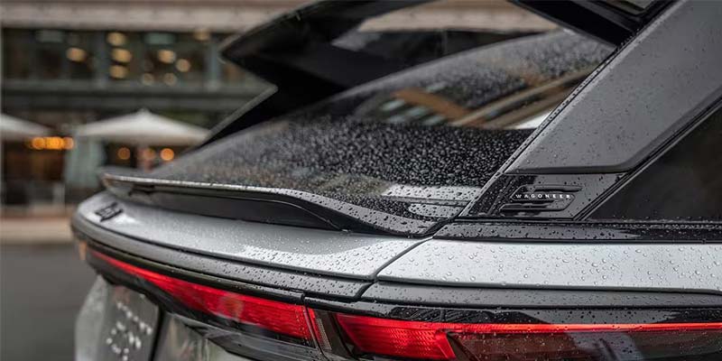 Rear view of a silver car with a spoiler, wet with raindrops