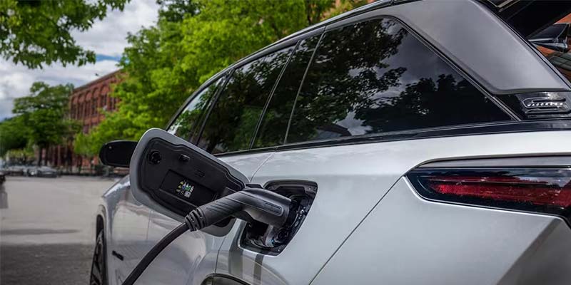 Close-up of a white SUV being charged with a plug
