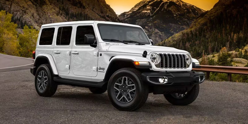 White four-door Jeep Wrangler on an asphalt road