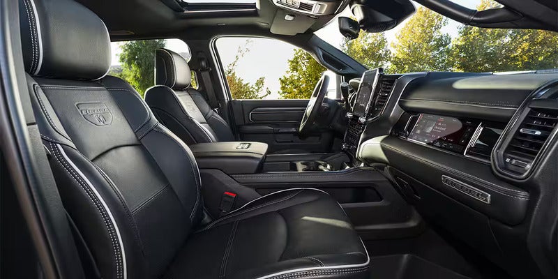 Interior of a black luxury car with white stitching on the seats, featuring a sunroof and a large infotainment screen.