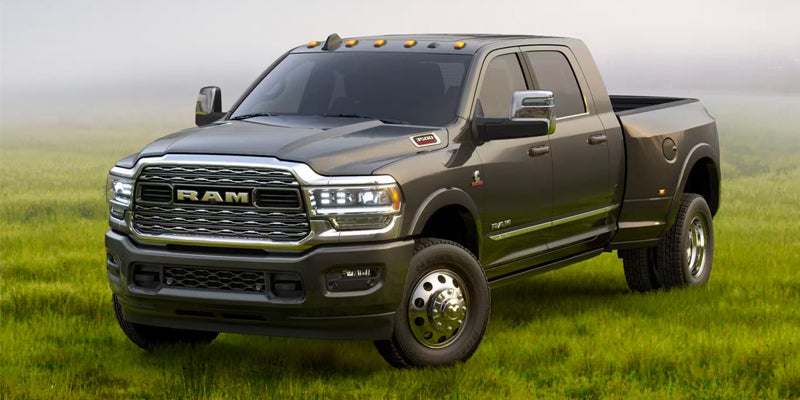 A gray RAM 3500 pickup truck with six wheels, facing left, parked on green grass.