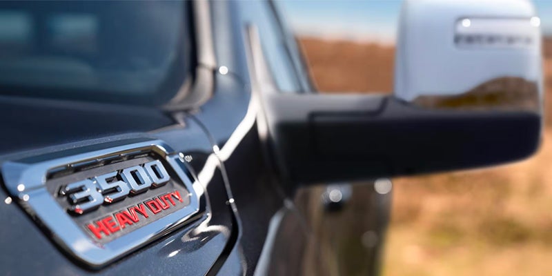 Close-up of a truck's side fender, showing a shiny silver badge with "3500 HEAVY DUTY" in black and red text.