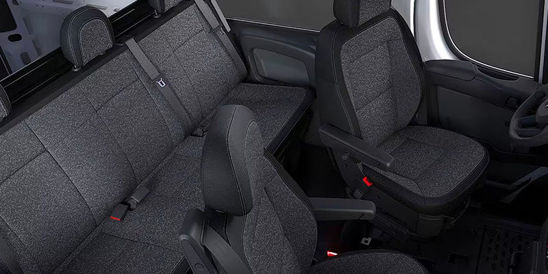 The interior of a vehicle features dark gray seats, with the front seats having armrests.