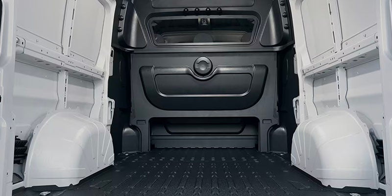 Interior of an empty cargo van with black anti-slip floor and white walls. The back wall has a window.